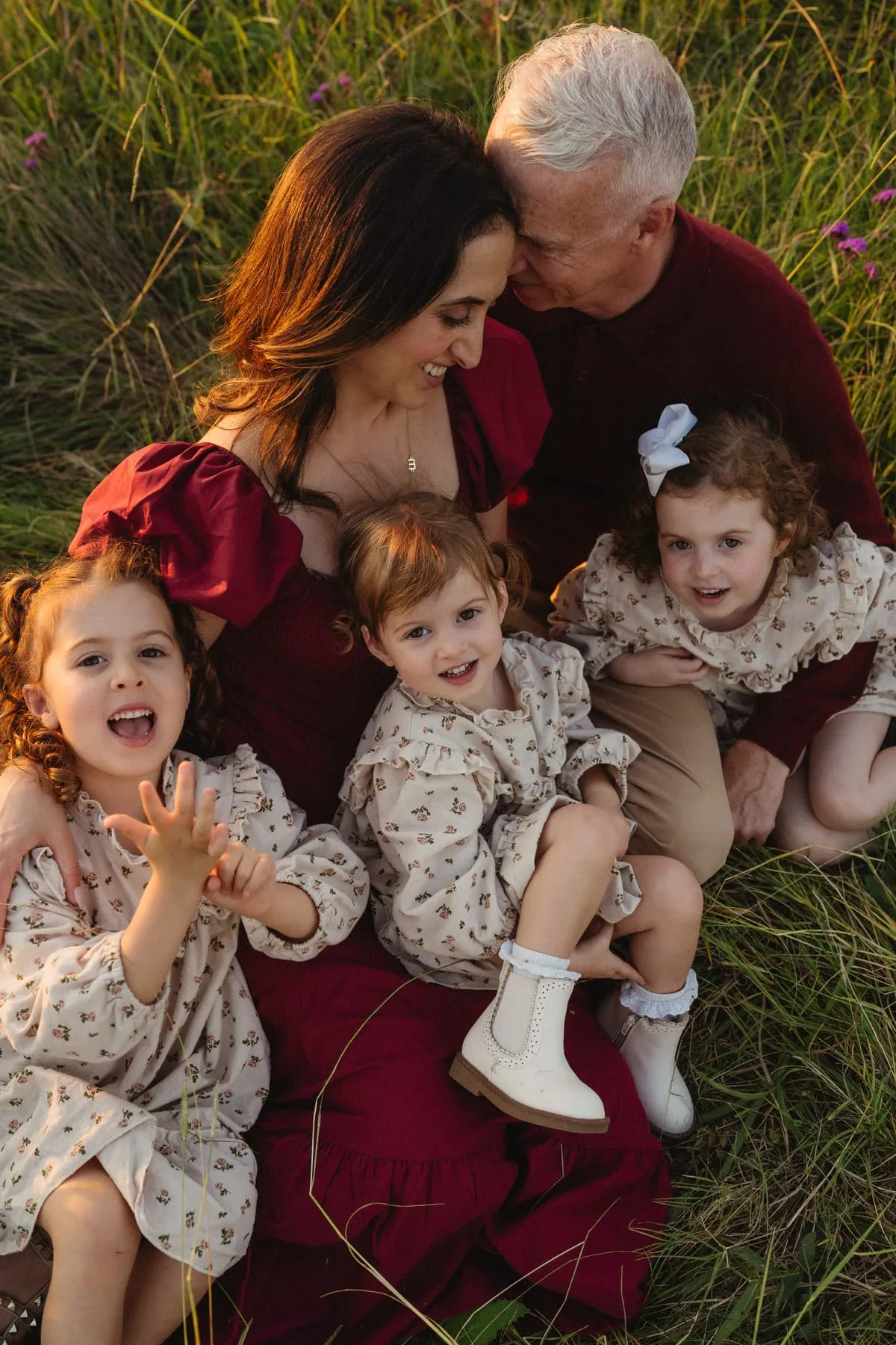 Three little girls cuddled up with their family in the long grass