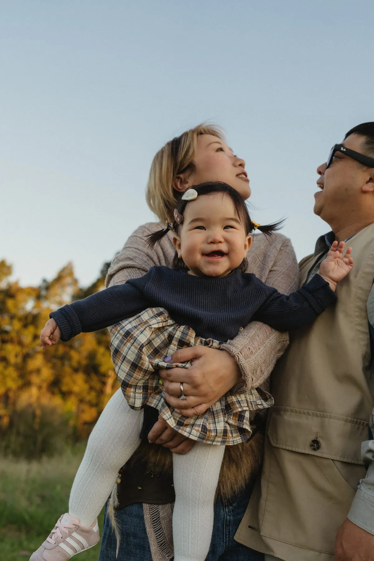 Parents lifting their laughing toddler into the air
