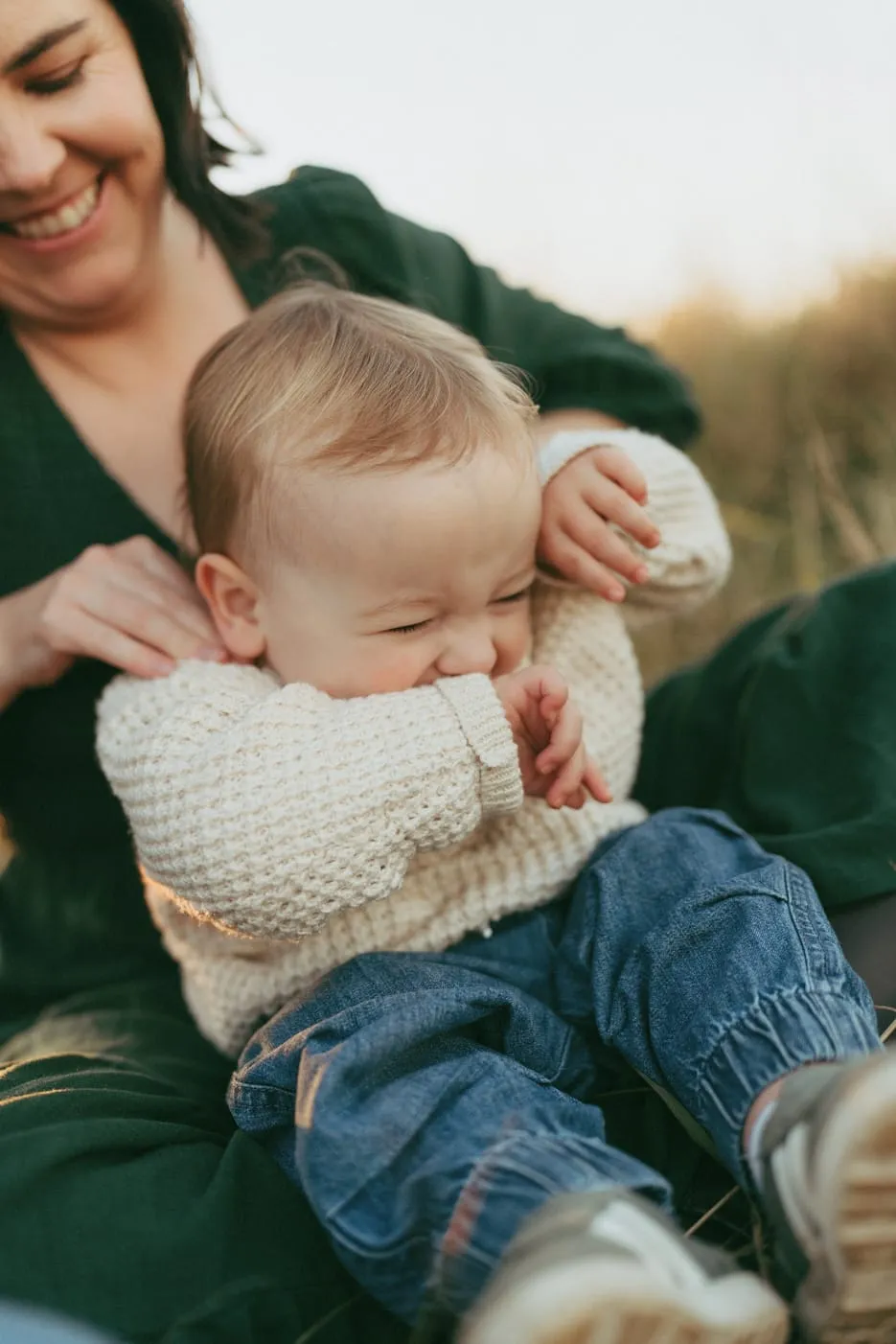 A toddler giggling in his mum’s lap