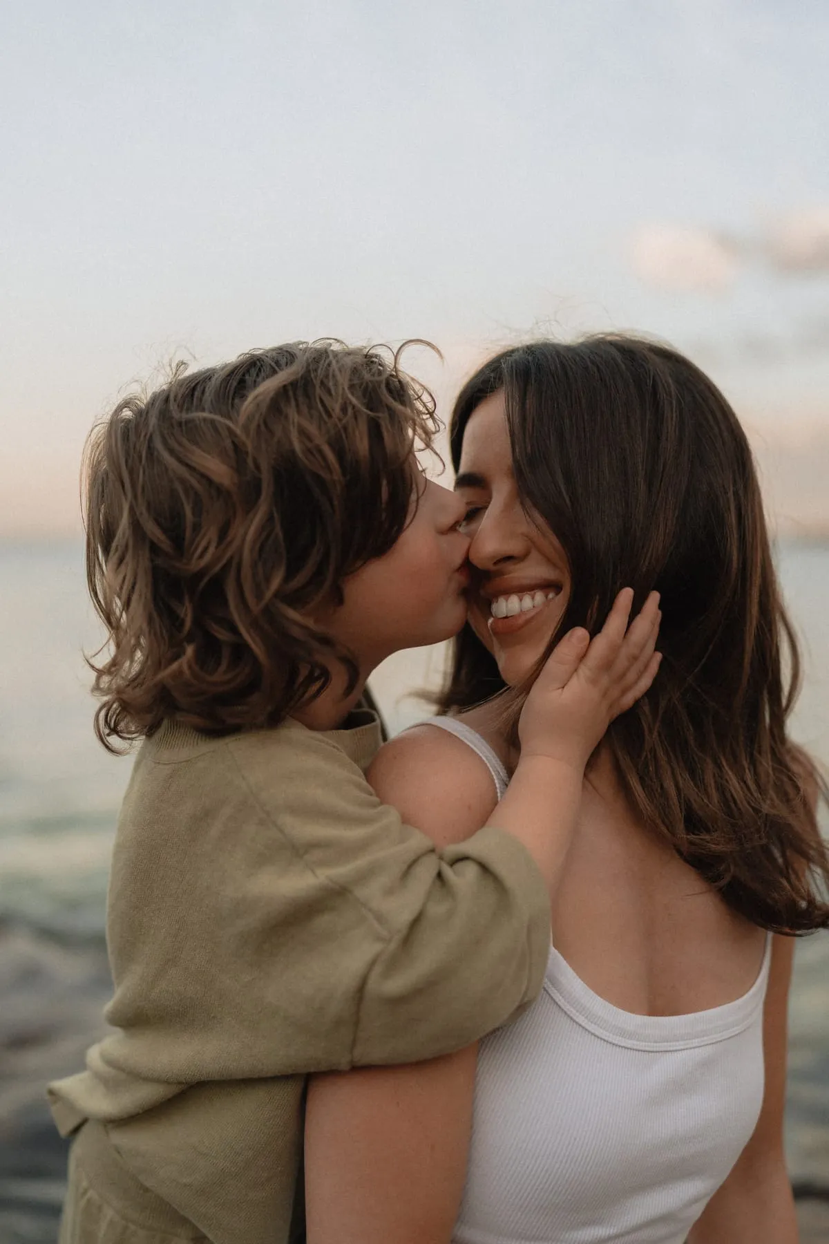 A mum and her son sharing a kiss by the sea