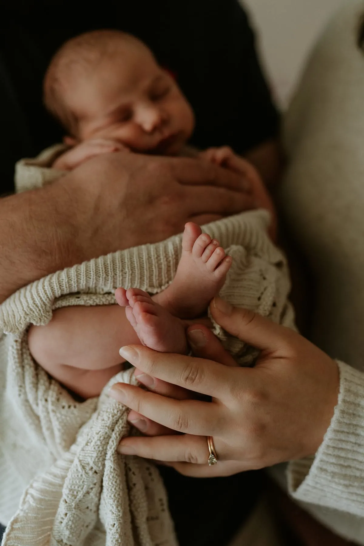 A sleeping newborn wrapped in a knit, held in two hands
