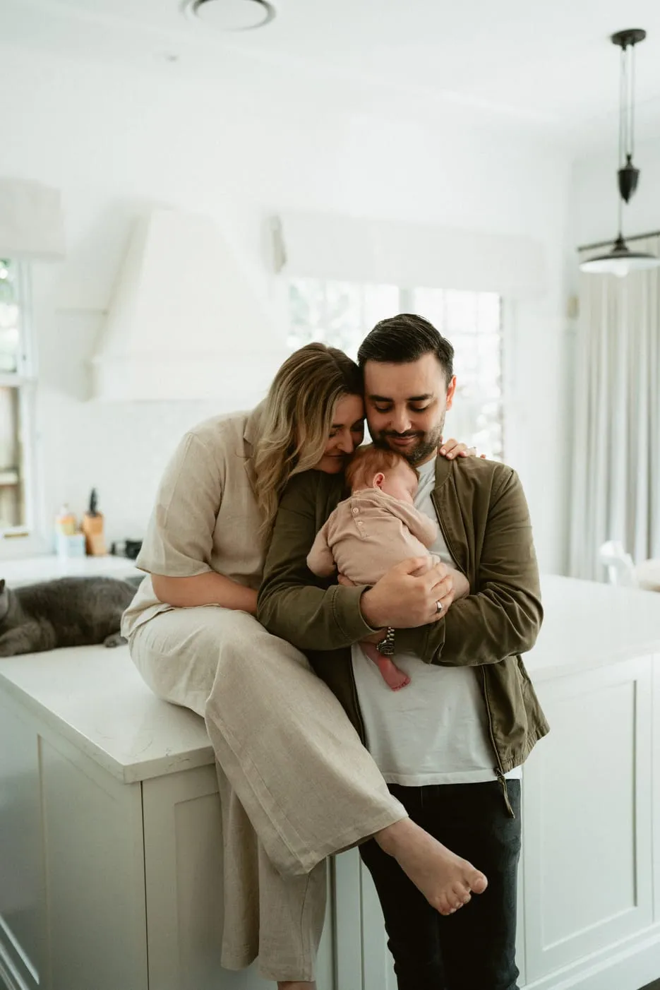 Parents cuddling their newborn in a bright kitchen