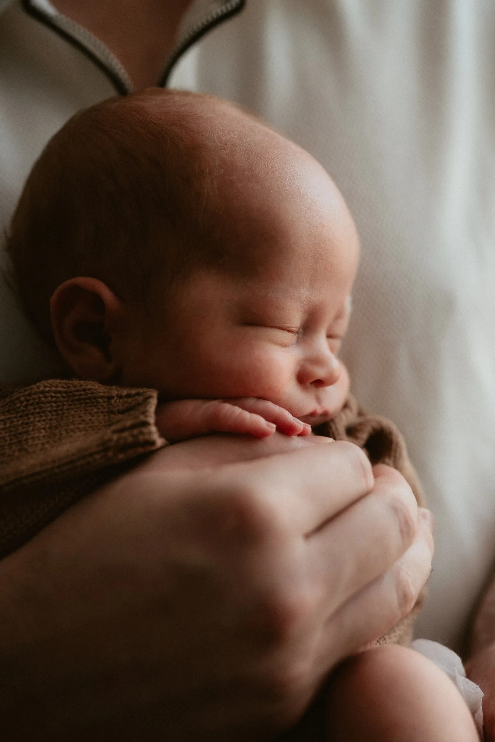 A sleeping newborn resting against a parent’s chest